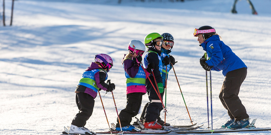 Skidledare pratar med barn i skidbacke