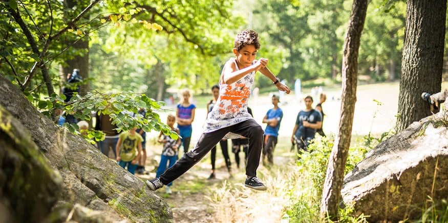 Ett barn hoppar mellan stenar under naturparkour