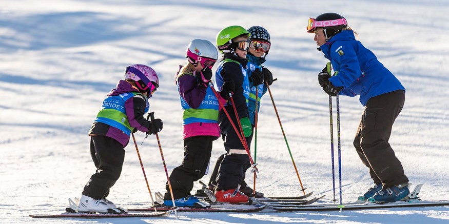 Barngrupp med skidlärare i skidbacken