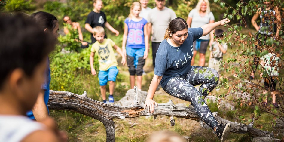 Ung person hoppar över en nedfallen gren i skogen