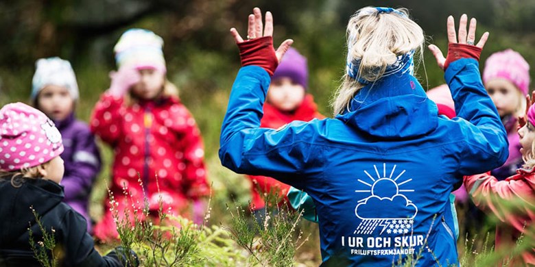 Förskolepedagog leker en lek med barngrupp i skogen