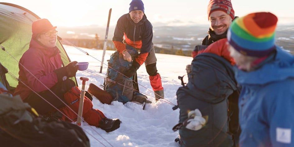 Grupp tältar i snön på fjället