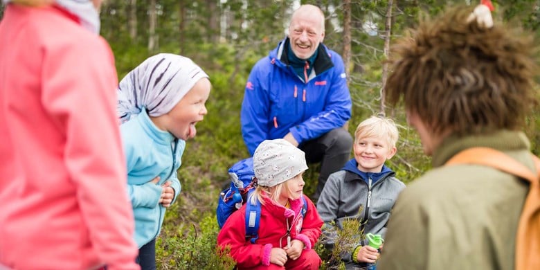Barngrupp sitter i skogen med Skogsmulle