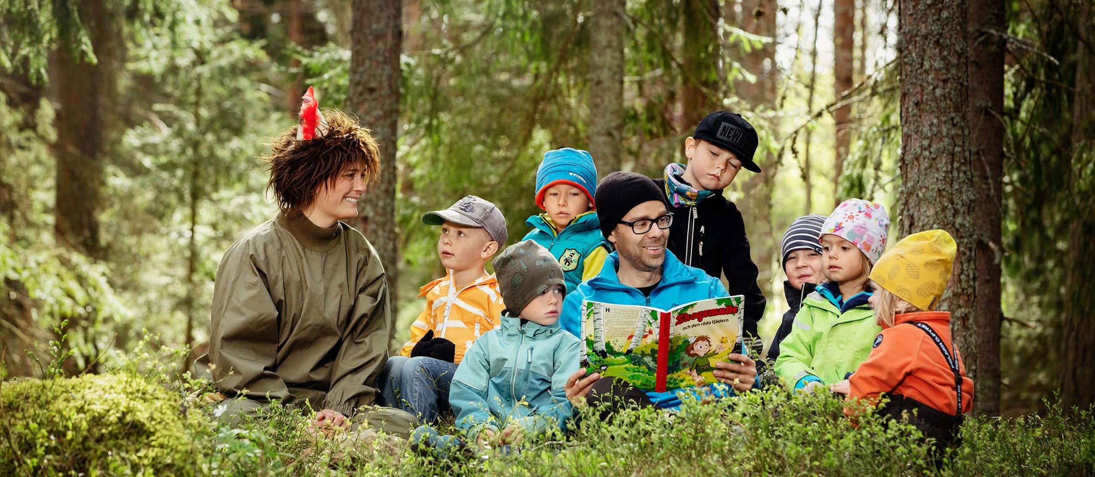 En grupp barn läser bok tillsammans med Skogsmulle och en ledare