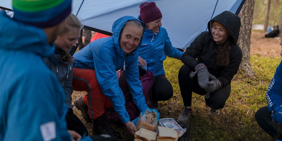 Grupp med ledare och deltagare plockar fram fika under vindskydd