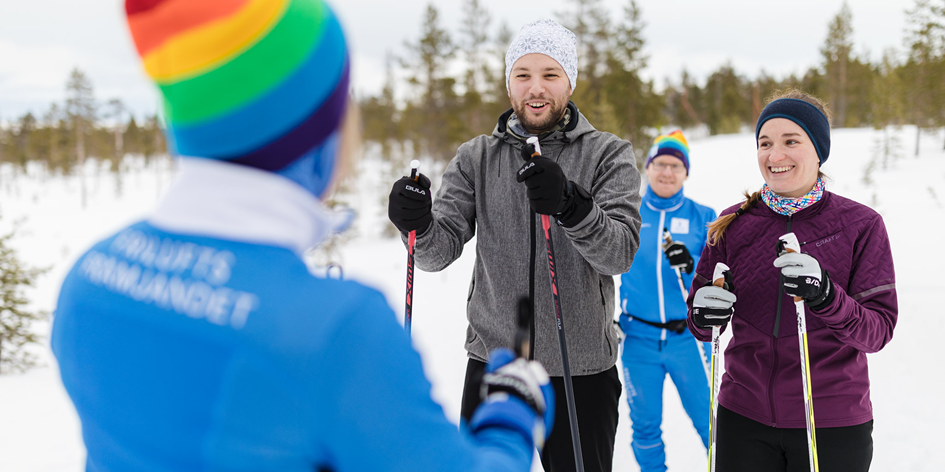 Tre längdskidåkare lyssnar på en ledare i längdskidor