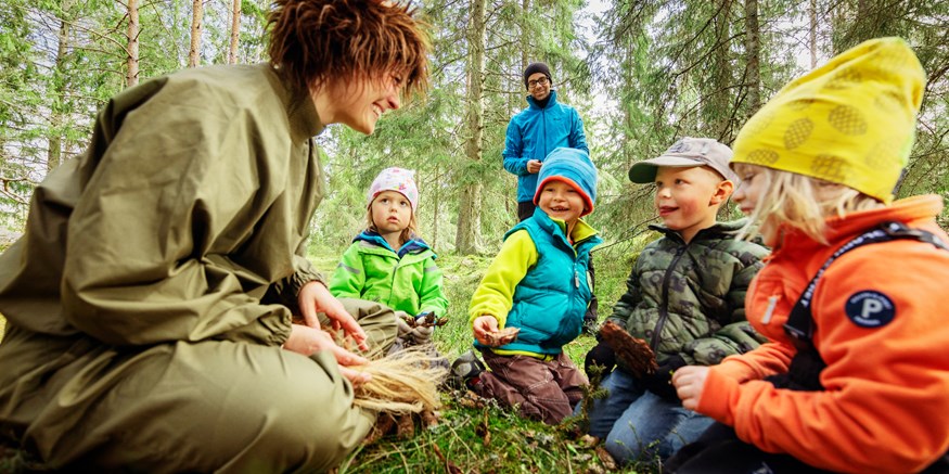 Barn sitter i ring i skogen och pratar och leker med Skogsmulle