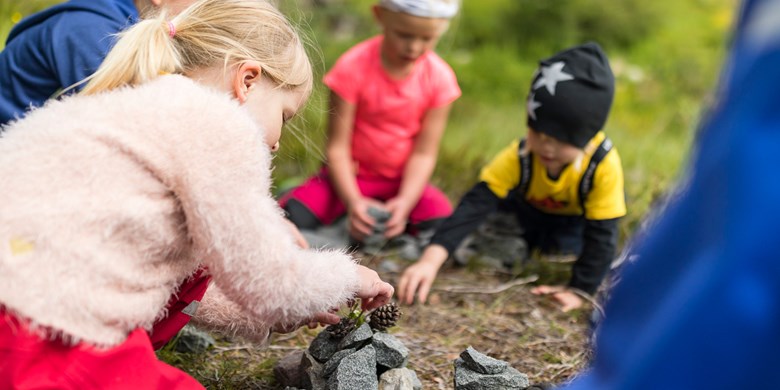 Barn i Skogsknopp leker med kottar i skogen