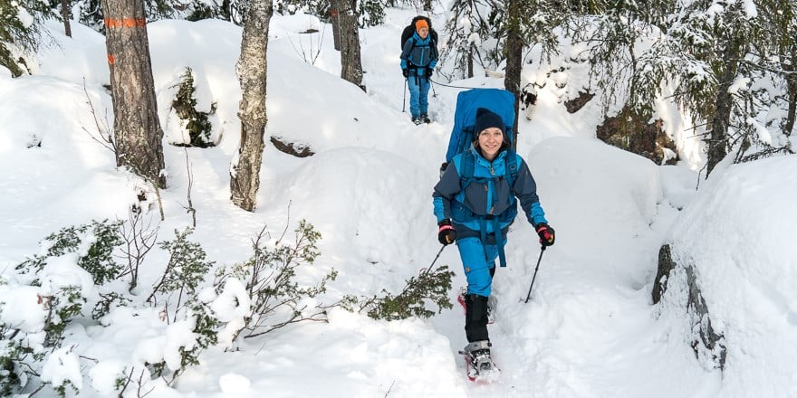 Personer vandrar i skogen med snöskor